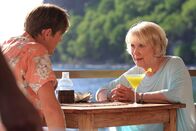 Death in Paradise – Humphrey (Kris Marshall, l.) und Tante Mary (Wendy Craig, r.) sitzen bei einem Cocktail beieinander. Mary hat ihrem Neffen etwas Wichtiges mitzuteilen.