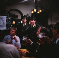 Polizeiinspektion 1 – Von links: Caspar (Gerd Fitz) feiert am Stammtisch noch nach der Sperrstunde die Geburt seines Kindes. Plötzl (Erich Hallhuber jun.) und Heinl (Elmar Wepper) weisen auf die Polizeistunde hin.