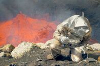 Planet der Vulkane – Ein Wissenschaftler im hitzebeständigen silbernen Anzug entnimmt Gesteinsproben am Rand des Marum-Lavasees in Vanuatu.