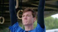 RUN4U – Niklas testet seine Griffkraft an den Ringen hängend.