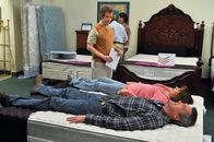 The Middle – Frankie (Patricia Heaton, in der Mitte liegend) ist begeistert, als Mike (Neil Flynn, vorne liegend) zustimmt, mit ihr ein neues Bett zu kaufen. Dabei lassen sie sich gern von einem Verkäufer (Jon Paul Burkhart, stehend) beraten. Da kommt Mike jedoch plötzlich auf die Idee, selbst ein Bett zu bauen ...