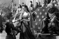 Die Ritter der Tafelrunde – Sir Lancelots (Robert Taylor, li.) leidenschaftlicher Kniefall vor der Königin (Ava Gardner, Mi.) erregt die Aufmerksamkeit des Hofes.