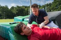 Notruf Hafenkante – Dr. Haase (Fabian Harloff, r.) verarztet den verunglückten Stabhochspringer Josh Baier (Daniel Finffrock, l.).