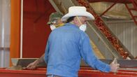 Fabriken der Superlative – Chili workers in masks with chilis on conveyor belts. (National Geographic/Alex Macdonald)
