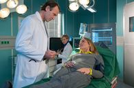 In aller Freundschaft – Bea Hölsch (Daniela Wutte, re.) ist mit Fieber umgekippt und hat sich einen Schlüsselbeinbruch zugezogen. Ihren behandelnden Arzt Dr. Martin Stein (Bernhard Bettermann, li.) bringt sie mit ihrem sehr anschmachtenden Verhalten in eine ziemlich unangenehme Situation. Auch Dr. Kathrin Globisch (Andrea Kathrin Loewig, mi.) ist ziemlich irritiert.