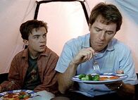 Malcolm mittendrin – Hal (Bryan Cranston, re.) und Malcolm (Frankie Muniz) haben sich in ein Zelt zurückgezogen, um wenigstens beim Essen nicht von Fledermäusen belästigt zu werden.
