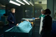 Kommissar van der Valk – Spurenanalyse: Van der Valk (Marc Warren, li.) und Lucienne (Maimie McCoy, re.) vertrauen auf ihren Pathologen Hendrik (Darrell D'Silva, re. hinten).