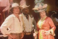 Unsere kleine Farm – Mrs. Oleson (Katherine McGregor, r.) kann es nicht fassen, dass die aristokratische Lehrerin in einem Güterwaggon reist. Charles (Michael Landon, l.) und Joe (Moses Gunn, M.) haben für diese Probleme keine Zeit.