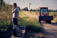 neoriginal: Like a Loser – Während Julian (Ben Münchow) am Feldrand pinkelt und telefoniert, hat er seine Tasche gefährlich nah an der Straße abgelegt. Ob der ominöse, sich nähernde Traktor da einfach vorbeifahren kann?