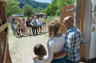 Problemos - Alle tot. Wir nicht. – Ankunft in einer abgeschirmten Welt: Victor (Eric Judor, re.) und seine Partnerin Jeanne (Célia Rosich, li.) betreten mit ihrem Kind die Kommune.