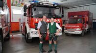 Hoagascht – Patrick Eisl (rechts) und HBI Christian Fischer, Kommandant der FF Altaussee (links) stehen in der Fahrzeughalle der FF Altaussee vor Feuerwehrautos