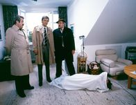 Tatort – In ihrer Wohnung wird die Leiche der jungen Apothekerin Ulla Brendl (Karin Kernke) gefunden. Stehend von links: Kriminalobermeister Brettschneider (Willy Harlander), Kriminalhauptmeister Lenz (Helmut Fischer) und Kriminalhauptkommissar Veigl (Gustl Bayrhammer).