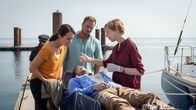 SOKO Wismar – Ole Janisch (Max Brauer, liegend) wird tot an Bord einer Jacht gefunden. Der Abiturient wollte eigentlich mit Freund Juuls Kampwirth die Welt umsegeln. Was ist auf der Jacht in der Nacht vor der geplanten Abreise passiert? Rechtsmedizinerin Helene Sturbeck (Katharina Blaschke, r.) kann ihren Kollegen Joost (Nike Fuhrmann, l.) und Pöhlmann (Dominic Boeer, M.) schon mal so viel sagen: Der junge Mann ist erschlagen worden. Doch dann hat jemand versucht, ihn wiederzubeleben. Wer hat Ole Janisch umgebracht? Warum musste der junge Mann sterben?
