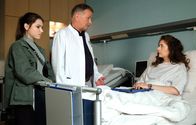 In aller Freundschaft – Dr. Roland Heilmann (Thomas Rühmann, mi.) vermutet, dass die Zyste, die die Ärzte an Anke Baumeisters (Amy Benkenstein, re.) Wirbelsäule gefunden haben, auch Bandwurmeier sein könnten. Anke hat einen Hund und engagiert sich in einem Tierheim. Auch Emma Brückner (Vivien Sczesny, li.) muss sich darauf testen lassen.
