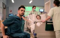 In aller Freundschaft – Dr. Ilay Demir (Tan Çağlar, li.) hat schon zum zweiten Mal einen jungen Mann erwischt, der bei seiner Patientin Ronja Mielitz (Alida Bohnen, liegend) war gleich bei Auftauchen eines Arztes weggerannt ist. Pfleger*innen: Kompars*innen