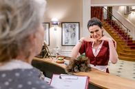 Sturm der Liebe – Shirin (Merve Çakır, r.) erfährt durch Alfons und Hildegard (Antje Hagen, l.), dass ein Filmstar zum Fürstenhof kommt, und hat eine Idee.
