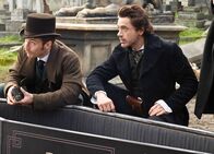 Sherlock Holmes – Sherlock Holmes Fragende Blicke am leeren Sarg: Jude Law als Dr. John Watson, Robert Downey Jr. als Sherlock Holmes
