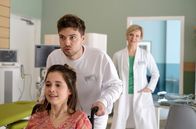 In aller Freundschaft – Amüsiert beobachtet Dr. Kathrin Globisch (Andrea Kathrin Loewig, hinten), wie Kris Haas (Jascha Rust, oben) versucht, die Pflegedienstleitung neben seinem Pflegerjob zu meistern. Auch die junge beinamputierte Patientin Dunja Wolke (Bianca Nawrath, vorn) hat so ihren Spaß mit Kris' Überforderung.