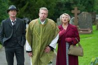 Father Brown – Inspector Valentine (Hugo Speer, l.), Father Brown (Mark Williams, M.) und Mrs. McCarthy (Sorcha Cusack, r.) versuchen, das blaue Kreuz aus der Kirche von Kembleford vor einem Raub zu schützen.