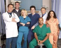 Scrubs - Die Anfänger – (4. Staffel) - Die Belegschaft des Sacred Heart Hospitals muss täglich mit neuen Überraschungen rechnen: J.D. (Zach Braff, M.), Turk (Donald Faison, 3.v.r.), Dr. Phil Cox (John C. McGingley, 2.v.r.), Hausmeister (Neil Flynn, 2.v.l.), Dr. Bob Kelso (Ken Jenkins, 2.v.l.), Elliot (Sarah Chalke, 3.v.l.), und Carla Espinosa (Judy Reyes, r.) ...