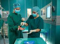 In aller Freundschaft – Während einer Operation kommt es zwischen Dr. Elena Eichhorn (Cheryl Shepard, links) und Dr. Martin Stein zum Streit. Elena ist durch Martins Eifersucht so aufgewühlt, dass sie einen Moment unkonzentriert ist und in ein Skalpell greift. Die Schnittwunde muss sofort von einer OP-Schwester (Komparsin) versorgt werden.
