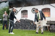 Hubert ohne Staller – Staller (Christian Tramitz, r.) droht, Jan Strobls (Martin Frank, 2.v.l. mit Komparse, l.) Handy zu erschießen, als dieser die brennende Garage filmt.