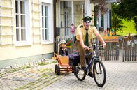 Hubert ohne Staller – Riedl (Paul Sedlmeir, r.) bemerkt nicht, dass er aussieht wie ein Clown und macht sich mit Lina (Carla Graßl, l.) im Bollerwagen auf den Weg zum Revier.