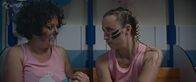 Derby Girl – Lola Bouvier (Chloé Jouannet, r.) kehrt zurück in die Mannschaft der "Cannibal Licornes". Für ihr bevorstehendes Spiel, möchte Marie-Josée (Salomé Diénis Meulien, l.) ihr einen Haargummi geben, doch Lola lehnt das Geschenk ab.