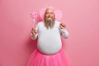 111 – Positive plump man has fun on theme birthday party, feels like fairy who makes dreams come true, chills with children, has thick beard and fat belly, poses with magic wand and wings on back.