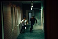 Hamilton – Hamilton (Jakob Ofterbro) und Lin Zheng (Jacelyn Parry), die nur Dank der Hilfe von Hamilton den brutalen Angreifern entkommen kann, rennen über einen Flur im Labor davon.