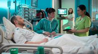 In aller Freundschaft – Irina Belova (Anna Schnumacher, 2.v.li.) und ihr Freund Friedrich Müggels (Eugen Knecht, li.) hatten einen Autounfall. Dr. Lilly Phan (Mai Duong Kieu, re.) hat bei Irinas Untersuchung neben zwei gebrochenen Rippen jedoch auch Anzeichen für ältere Verletzungen festgestellt. Für Pflegerin Jasmin (Leslie-Vanessa Lill, hi.) bestätigt das ihre Vermutung, dass Friedrich gegenüber seiner Freundin gewalttätigt ist.