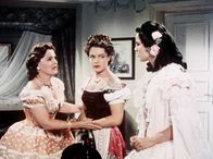 Sissi – Ludovika (Magda Schneider, li.) bereitet ihre älteste Tochter Helene (Uta Franz, re.), genannt Nene, auf das Treffen mit dem österreichischen Kaiser vor. Die stürmische, junge Sissi (Romy Schneider) stört da nur.