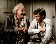 Die Waltons – Sam Walton (Will Geer, l.) schwelgt in seinen Erinnerungen an seine Querfeldeinrennen. John-Boy (Richard Thomas, r.) hört ihm gerne zu.