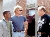 MacGyver – Kelvin (Vonte Sweet, l.) und MacGyver (Richard Dean Anderson, M.) werden von Sergeant Mullins (James Mathers, r.) verhört.