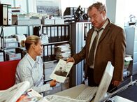 Der Bernsteinfischer – Auf einem Foto erkennt Karolines (Sonsee Neu) Chefredakteur Manfred (Michael Hanemann) die wahre Identität ihres neuen Geliebten.