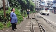 Legendäre Zugabenteuer – Die 90 Kilometer lange Strecke nach New Jalpaiguri führt oft mitten durch kleine Städte. Hier wartet eine Mitarbeiterin darauf, die Weiche für den Zug umzustellen.