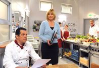 Sturm der Liebe – ARD STURM DER LIEBE FOLGE 1309 Uhr im ERSTEN. Charlotte (Mona Seefried, r. mit Komparsen) amüsiert sich über Andrés (Joachim Lätsch, l.) misslungenen Verjüngungsversuch.