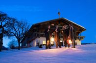Hoagascht – D`Stommtischsänger stehen als Anklöpfler in der blauen Stunde vor einem Bauernhaus in der Winterlandschaft.