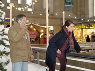 In aller Freundschaft – Bei Elena Eichhorn (Cheryl Shepard, rechts), die im weihnachtlich geschmückten Hauptbahnhof den Eisläufern zusieht, setzen plötzlich die Wehen ein. Sie bittet einen Passanten, einen Krankenwagen zu rufen.