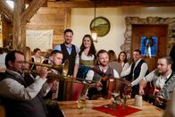 Servus Musikantenstammtisch – Moderatoren Conny Bürgler und Richard Deutinger (hinten) mit Musikgruppe "Die fröhlichen Waschbären" in der Stube der Mostschänke Hussenbauer.