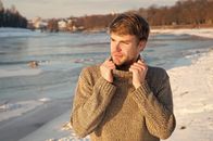 Ovanti Strickdesign – Man unshaven handsome hipster in knitwear sweater high collar stand frozen river background. Winter landscape beauty. Man enjoy winter sunny day. Winter knitted clothes warming up. Winter fashion.