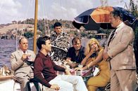 Topkapi – v.l.n.r.) Cedric (Robert Morley), Walter (Maximilian Schell), Giulio (Gilles Ségal), Hans (Jess Hahn) und Elizabeth (Melina Mercouri)) gratulieren Mr. Simpson (Peter Ustinov, ganz re.), der erfolgreich ihre präparierte Limousine nach Istanbul eingeschleust hat.