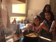 Ich bin Ich – May-Lin (li.) rührt in der Pfanne die leckeren Nudeln. Das ist gar nicht so einfach. Ihre zehnjährige Schwester Yuc-Lin (re.) hilft ihr dabei.