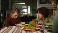 Saïd und Anna – Anna ist geknickt. Sie mag den Spinat nicht, den Sameer auf die Pizza getan hat.