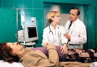 In aller Freundschaft – Dr. Globisch (Andrea Kathrin Globisch, Mitte) und Prof. Simoni (Dieter Bellmann) trauen ihren Augen nicht, als die schwangere Pia (Hendrikje Fitz) nach einem Verkehrsunfall in die Sachsenklinik eingeliefert wird.