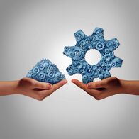 Große Inspektion – Technology management concept as a hand holding a group of mixed disorganized gears and cogs with another person presenting the machine parts put together as a symbol for a business manager connecting the ingredients for success.