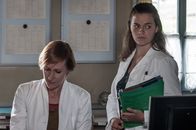 Der Bergdoktor – Irena Bornholm (Nicole Beutler, l.) reicht Lilli Gruber (Ronja Forcher, r.) einen Stapel Akten zur Bearbeitung.