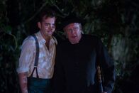 Father Brown – Sid (Alex Price, l.) und Father Brown (Mark Williams, r.) verstecken sich im Wald. Sie beobachten die Dorfbewohner, die sich um einen Stein versammelt haben, um ein geheimes Ritual zu vollziehen.
