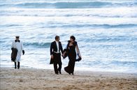 Stavisky – Stavisky (Jean-Paul Belmondo) und seine Frau Arlette (Anny Duperey) machen einen Strandspaziergang.