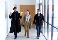 Sherlock – Dr. Watson (Martin Freeman) und die Ärztin Molly (Louise Brealey) staunen nicht schlecht, als Sherlock Holmes (Benedict Cumberbatch, li.) ihnen zwei Chipstüten als Mittagessen präsentiert.